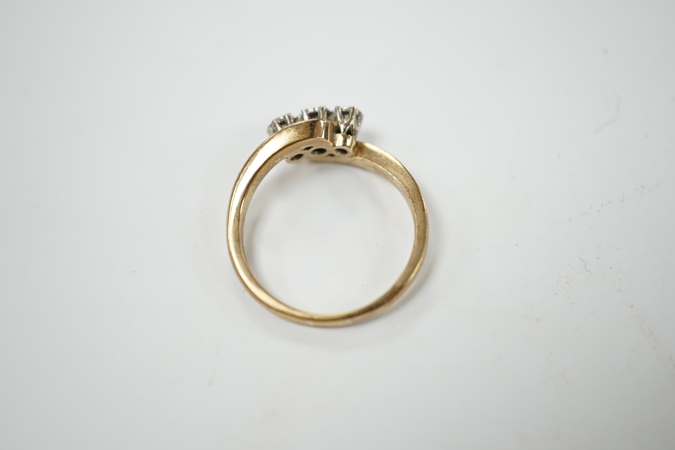A modern 9ct gold and three stone diamond set cross-over ring, size P/Q, gross weight 3.4 grams. Condition - fair